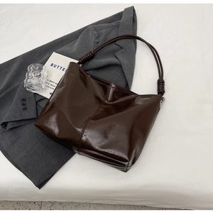 Detail view of coffee brown faux leather tote with unique pleated knots on the strap