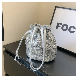 Détail du sac seau à paillettes argentées avec cordon de serrage sur une surface noire