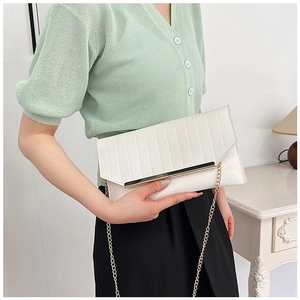 Detail der weißen geometrisch gesteppten Umschlag-Clutch mit goldener Kette