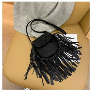 Detail of black faux suede crossbody bag featuring long fringe tassels and saddle flap