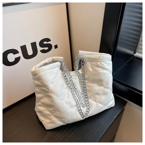 Detailed close-up of quilted white tote bag with silver metal chain straps and leather texture