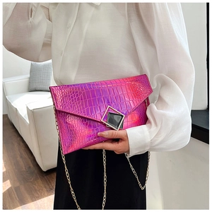 Macro shot of the vibrant magenta crocodile texture clutch with gold chain strap detail