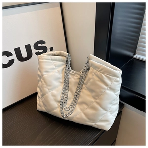 Detailed view of white quilted tote bag featuring silver chain straps and diamond patterns