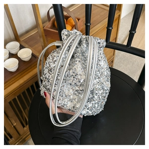 Détail du sac seau à paillettes argentées avec fermeture à cordon sur une chaise