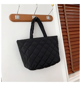 Close-up of black quilted tote bag with classic diamond pattern and padded handles