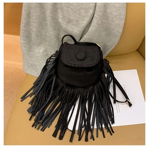 Close-up of black suede saddle bag featuring bohemian fringe and woven trim details