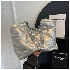 Close-up of silver quilted tote bag with metallic chain straps and diamond texture