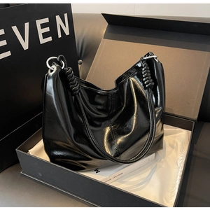 Detail of glossy black shoulder bag in a gift box with silver ring metal hardware