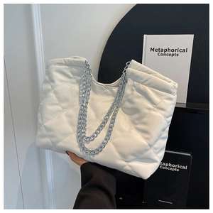 Close-up of white quilted tote bag with silver chain straps and leather texture
