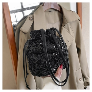 Détails d'un sac seau noir à paillettes avec cordon de serrage et fine bandoulière en cuir