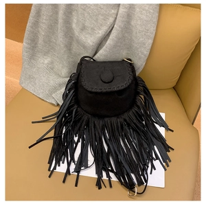 Macro shot of black suede saddle bag featuring long fringe tassels and golden hardware detail