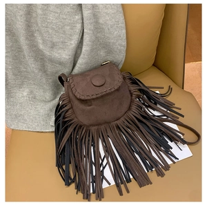 Detailed view of bohemian faux suede saddle bag featuring braided trim and long fringe tassels