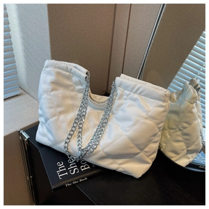 Detail of white quilted puffer tote bag with glossy finish and silver chain straps