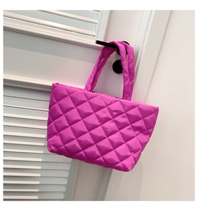 Detail of vibrant pink quilted tote bag with shiny finish hanging on a white door