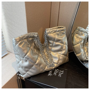 Close-up of silver quilted tote bag featuring metallic gloss finish and chain handles