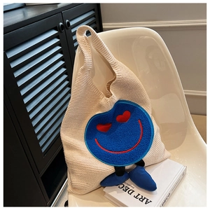 Λεπτομέρεια πλεκτής τσάντας με σχέδιο smiley και 3D πόδια σε μίνιμαλ καρέκλα