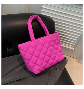 Detailed close-up of quilted fuchsia nylon tote bag texture on a dark leather chair