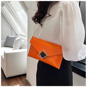 Detail of bright orange stone pattern envelope bag with gold chain and metal buckle