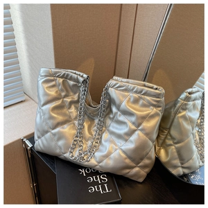 Detail of silver metallic quilted tote bag with chain strap reflected in a mirror