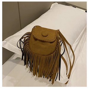 Close-up of brown suede saddle bag featuring long tassels and stitched flap details