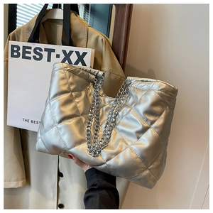 Close-up of metallic silver quilted tote bag featuring plush texture and silver chain straps