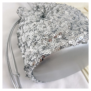 Détail d'un sac seau à paillettes argentées avec fermeture à cordon et garniture en cuir