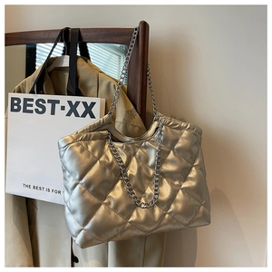 Detail of silver quilted tote bag with metallic chain straps on a wooden hanger