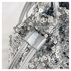 Détail des paillettes argentées et du cordon en cuir sur un sac seau élégant
