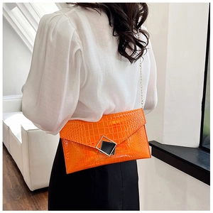 Chic orange crocodile pattern envelope bag with gold chain strap shown on shoulder