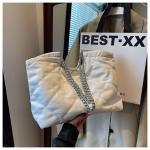 Close-up of white quilted tote bag with shiny leather texture and silver chain strap