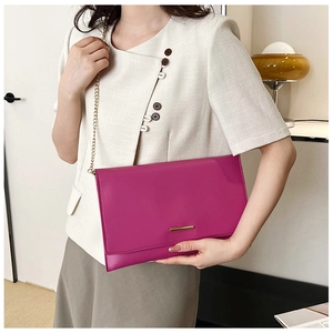 Detail of rose red geometric clutch bag with gold metal trim and fine chain strap
