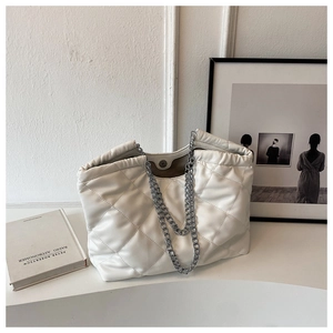 Macro view of cream quilted tote bag with silver chain straps and magnetic closure