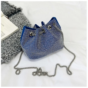 Détail d'un sac seau bleu orné de strass brillants avec une bandoulière en chaîne argentée