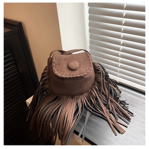 Detailed view of brown suede saddle bag featuring long fringes and bohemian stitch accents