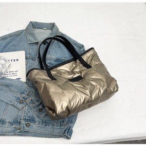 Détail du sac cabas matelassé doré champagne avec logo noir et poignées élégantes