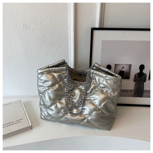 Detail of silver quilted tote bag with chunky metal chain strap and magnetic snap closure