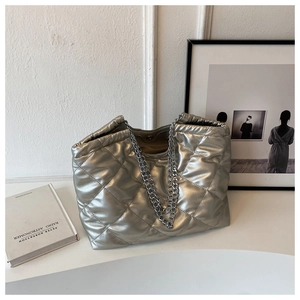 Detail of silver quilted puffer tote bag with metallic texture and double chain handles