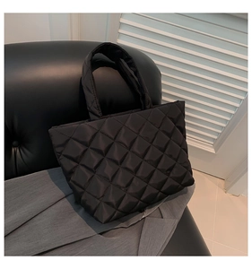 Detailed view of black quilted tote bag with classic diamond stitch and puffer texture