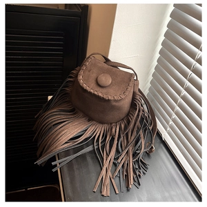 Close-up of brown faux suede saddle bag featuring long fringe tassels and hand-stitched seams