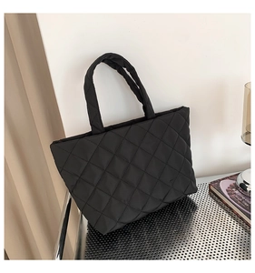 Detailed close-up of a black quilted tote bag with soft rhombus pattern and durable handles