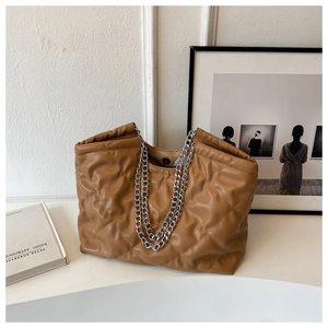 Detail of caramel brown quilted tote bag showing diamond stitching and silver chain straps