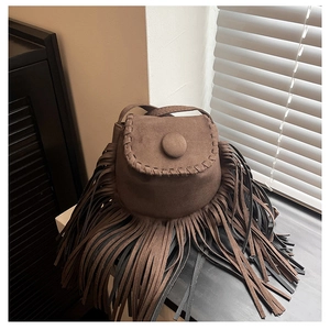 Detail of suede crossbody bag with long tassels, fringe accents and woven stitching