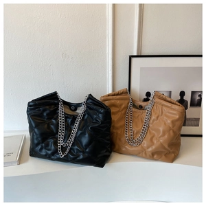 Close-up of quilted tote bags in black and tan with silver chain straps and magnetic closure