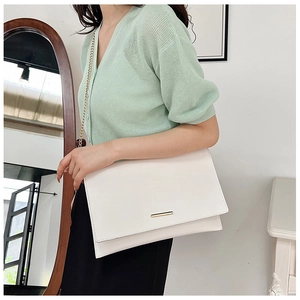 Close-up of cream envelope crossbody bag with gold metal clasp and elegant chain strap