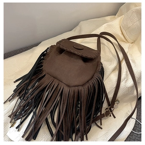 Close-up of brown suede saddle bag featuring dense tassel details and fine stitching