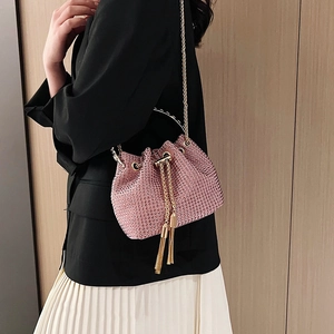 Sac seau rose avec strass, chaîne dorée et franges porté par un mannequin en intérieur