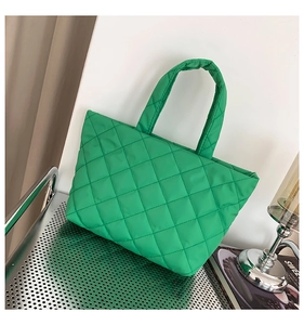 Detail of green quilted tote bag with diamond pattern on silver metal shelf