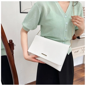 Detailed view of white envelope crossbody bag with gold metal trim and elegant chain strap