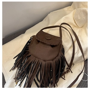 Close-up of a brown suede saddle bag featuring long tassels and rustic whipstitch details