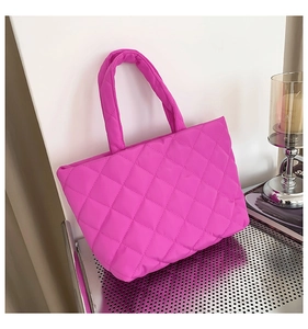 Detail of hot pink quilted nylon tote bag featuring classic diamond stitching on metal shelf